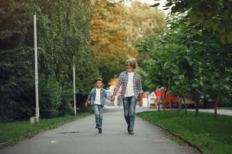 A grandfather and grandson walking through the park