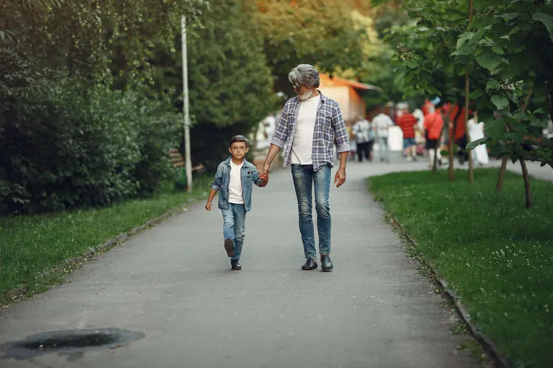A grandfather holding his grandson's hand on a walk