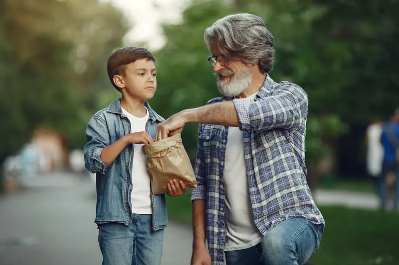 A grandfather and grandson sharing a snack on a walk