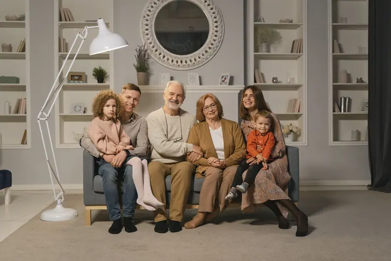 A grandfather surrounded by family on the living room couch