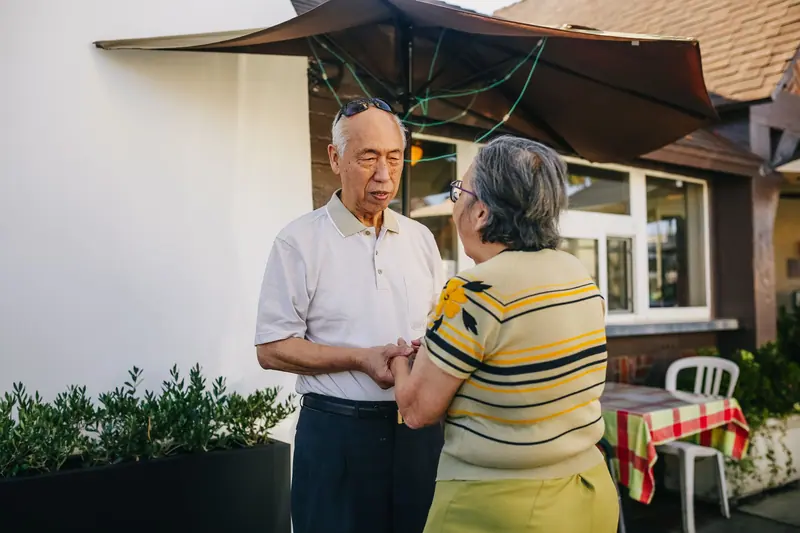 A married couple holding hands on their back patio