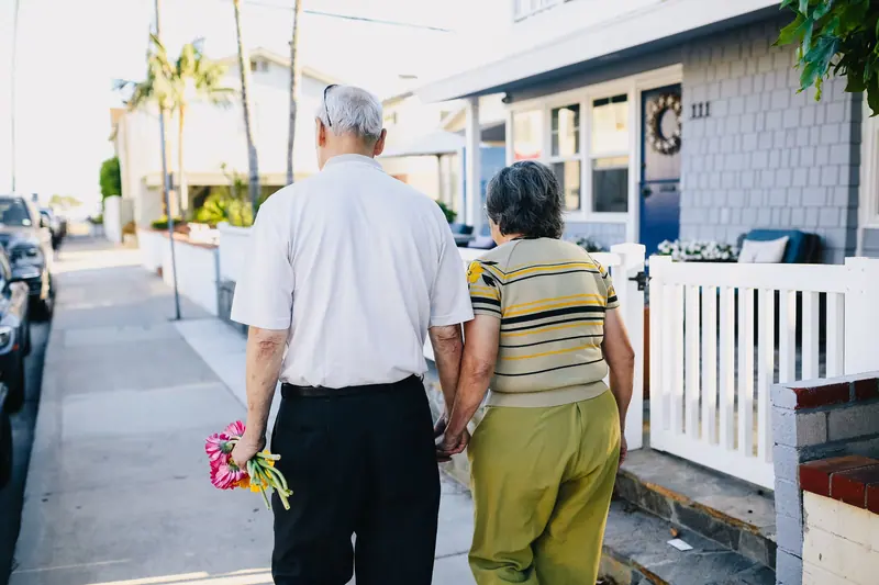 A couple walking hand in hand down a sunny sidewalk