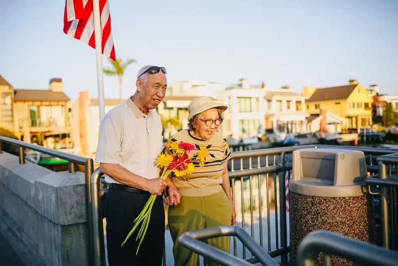 An older couple holding hands with flowers