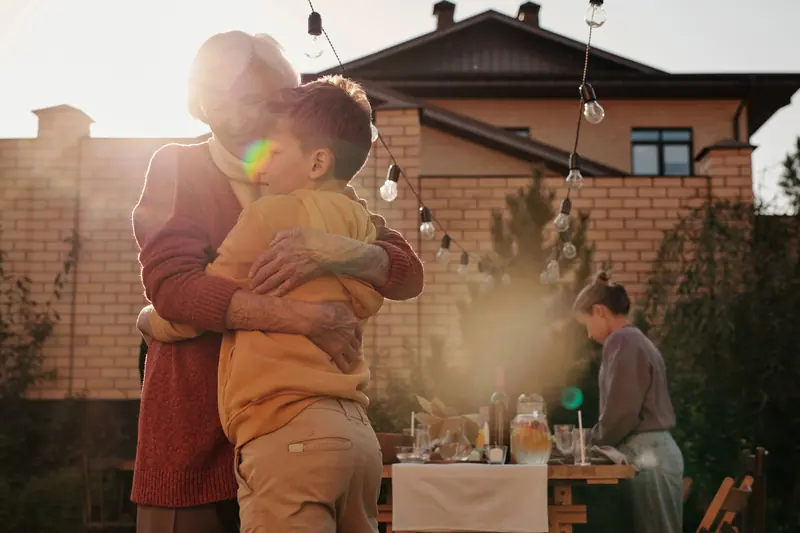 A grandmother hugging her grandson in the backyard