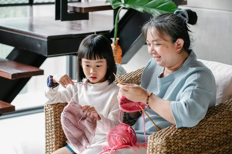 A grandmother teaching her granddaughter to knit