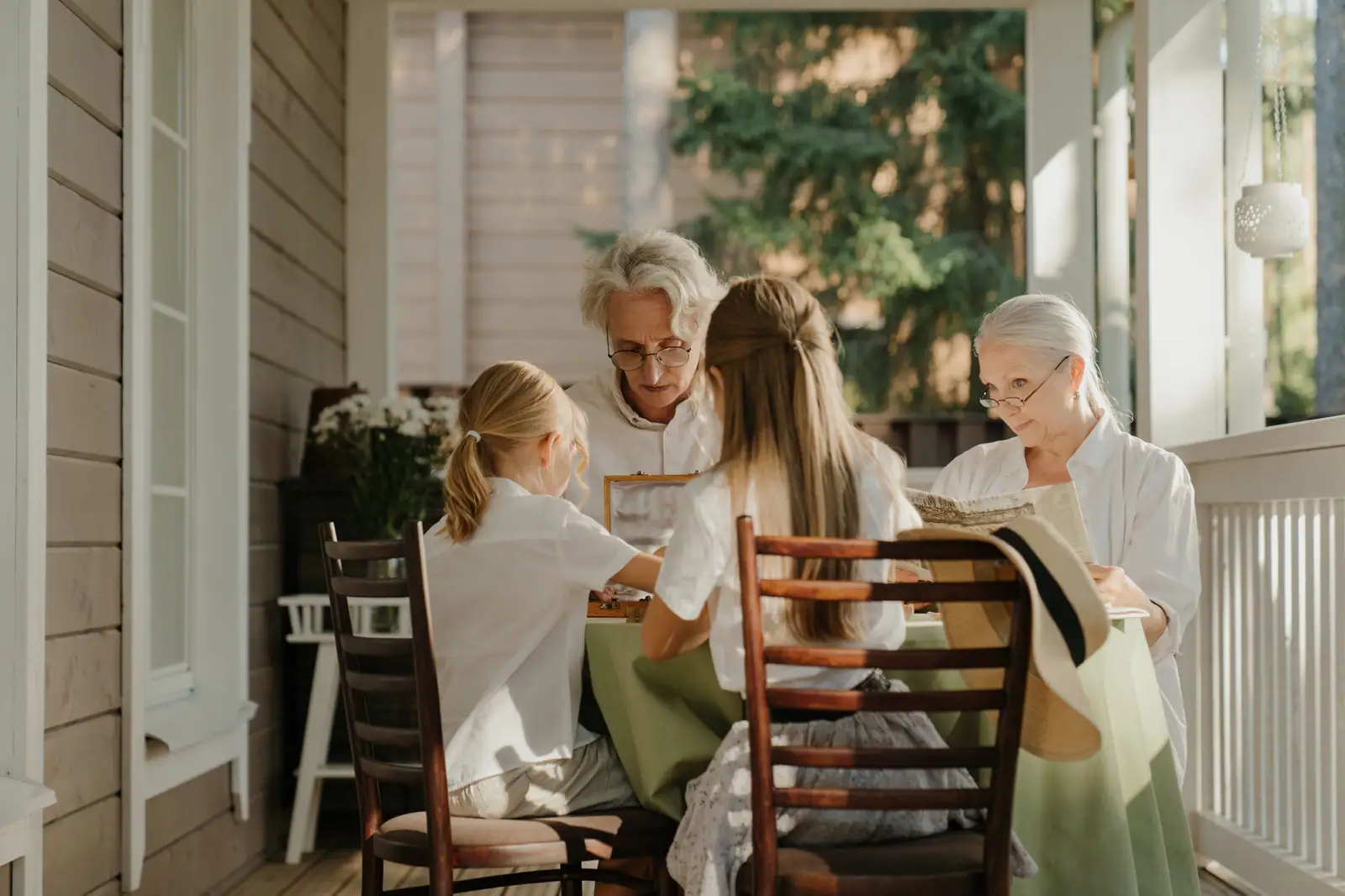 Three generations of a family laughing together on a sunlit front porch