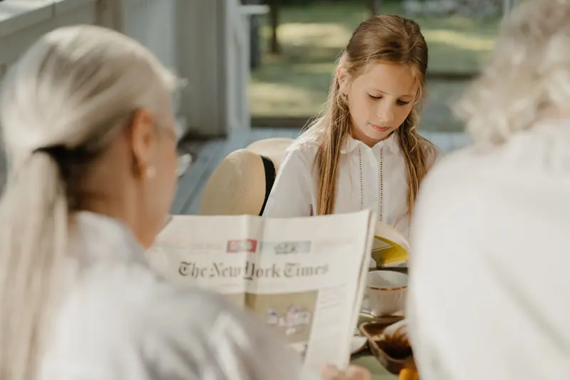 A granddaughter reading the newspaper aloud to her grandmother