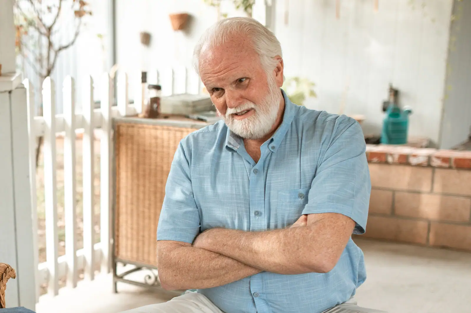 A man on his porch with his arms crossed, listening