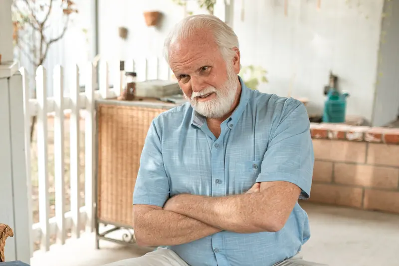 A man on his porch with his arms crossed, listening