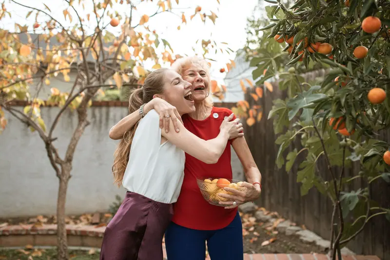 A granddaughter and grandmother hugging under the orange tree