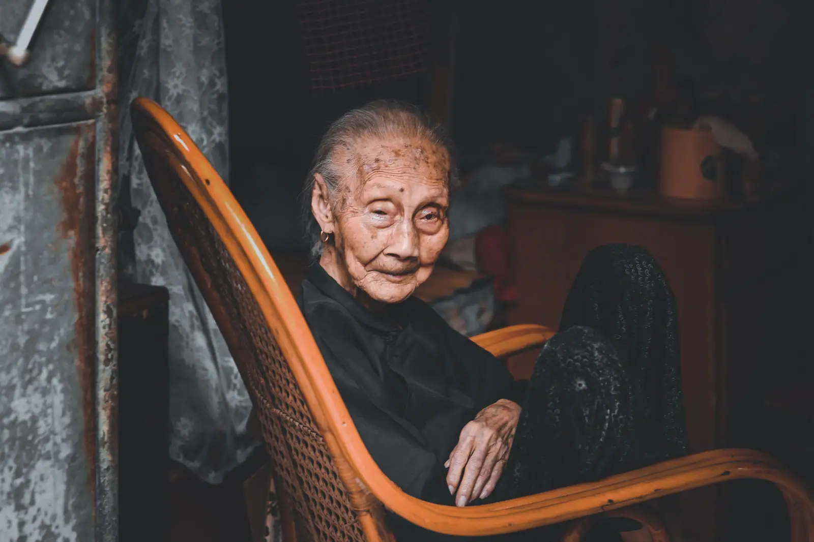 A woman in her nineties resting in her bentwood rocking chair in a lamplit room