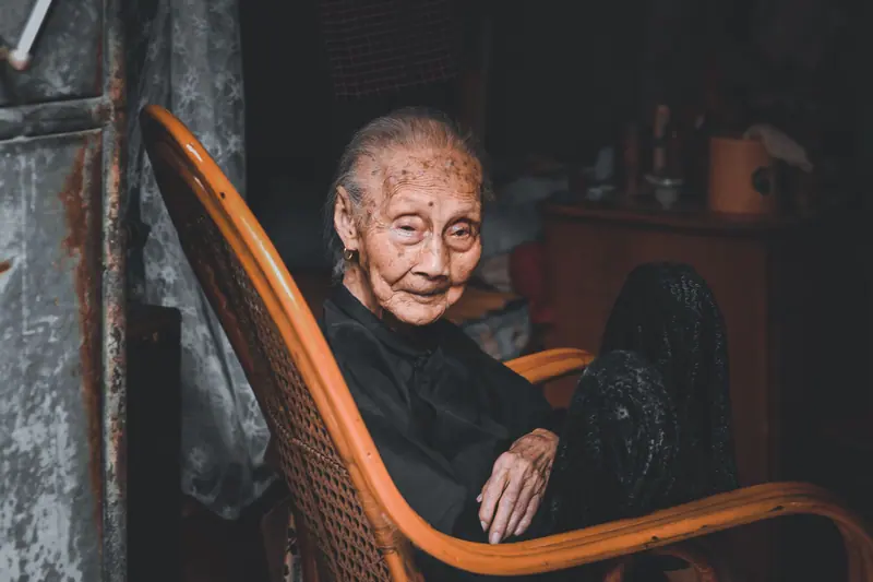 A woman in her rocking chair in a lamplit room