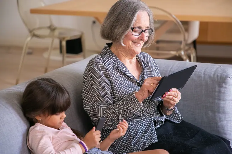 A grandmother and granddaughter on the sofa with a tablet
