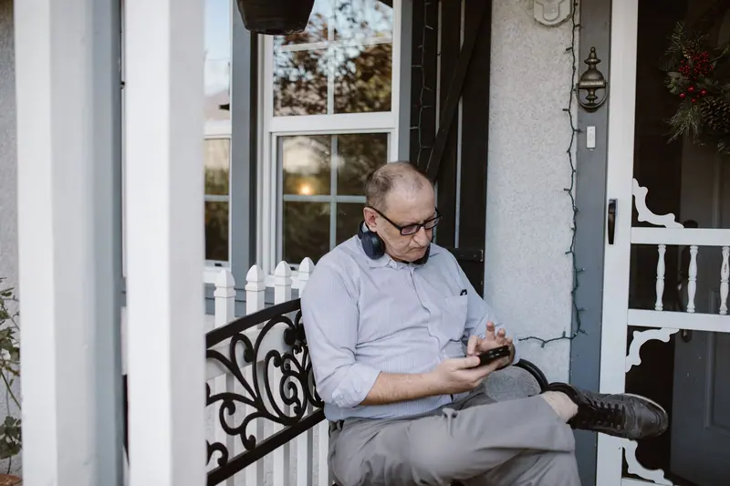 A man reading on his phone on the porch