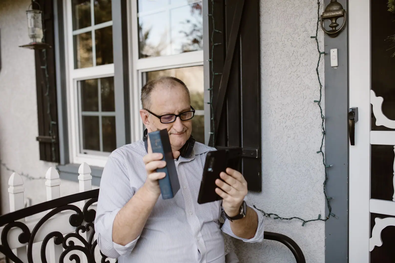 A smiling grandfather on a video call with his family from the front porch