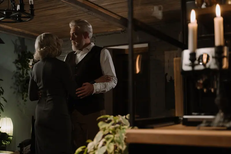 A married couple slow dancing by candlelight at home