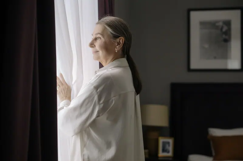A woman standing at her bedroom window