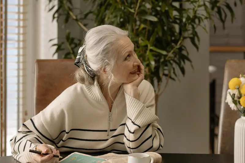 A woman smiling as she works a crossword at the kitchen table