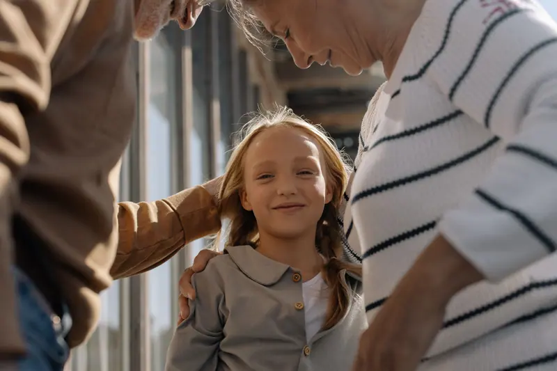 A granddaughter wrapped in her grandparents' arms