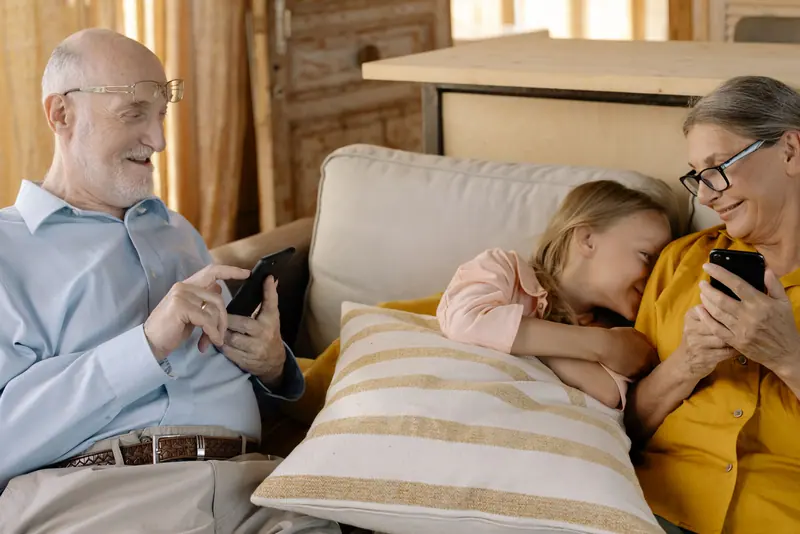 Grandparents and granddaughter sharing photos on the couch