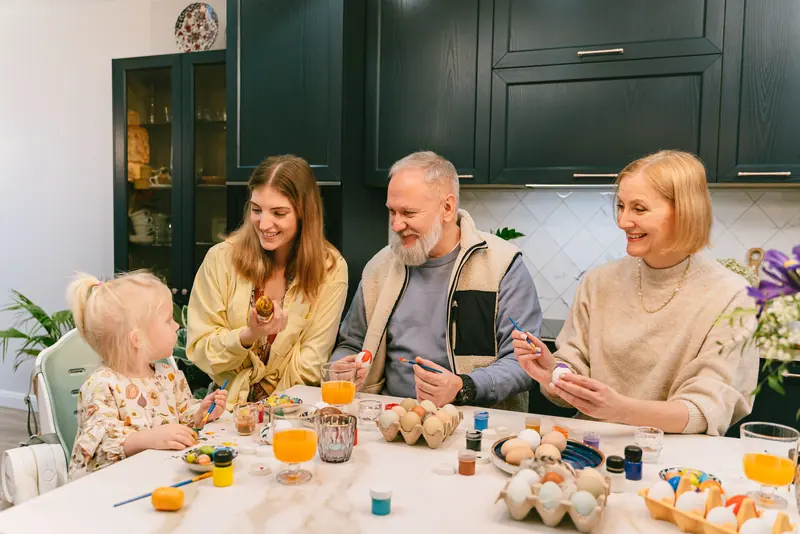 Three generations dyeing Easter eggs together at the kitchen table