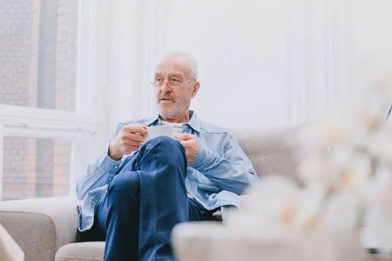 A man with his tea on the sofa