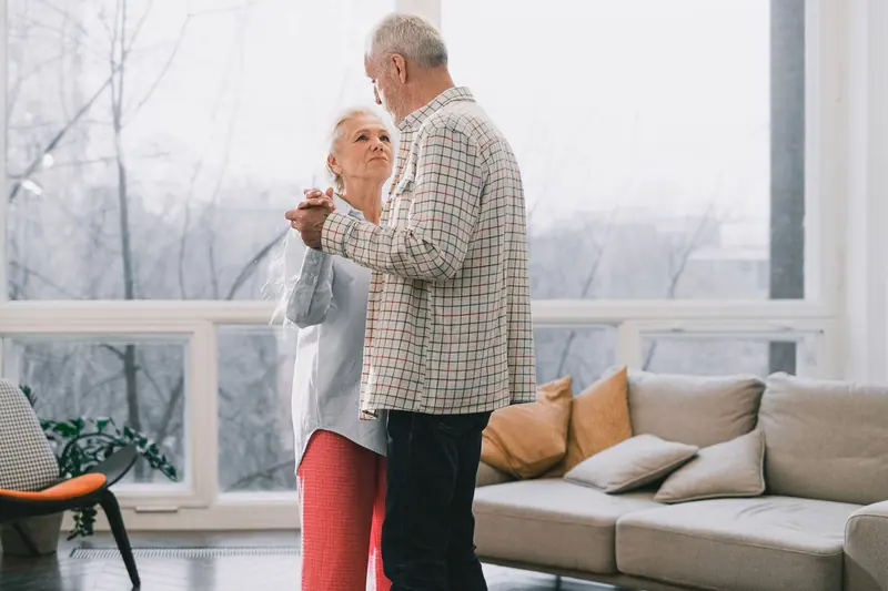 An older couple dancing together in their sunny living room