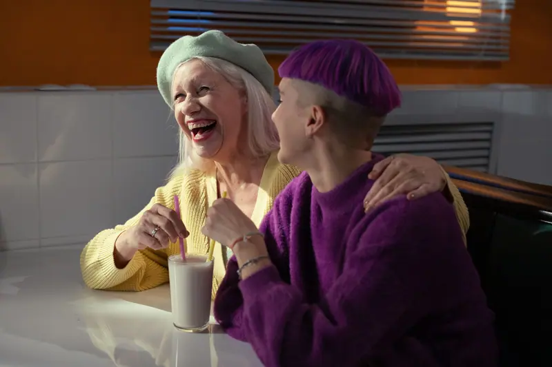 A grandmother and granddaughter laughing over milkshakes
