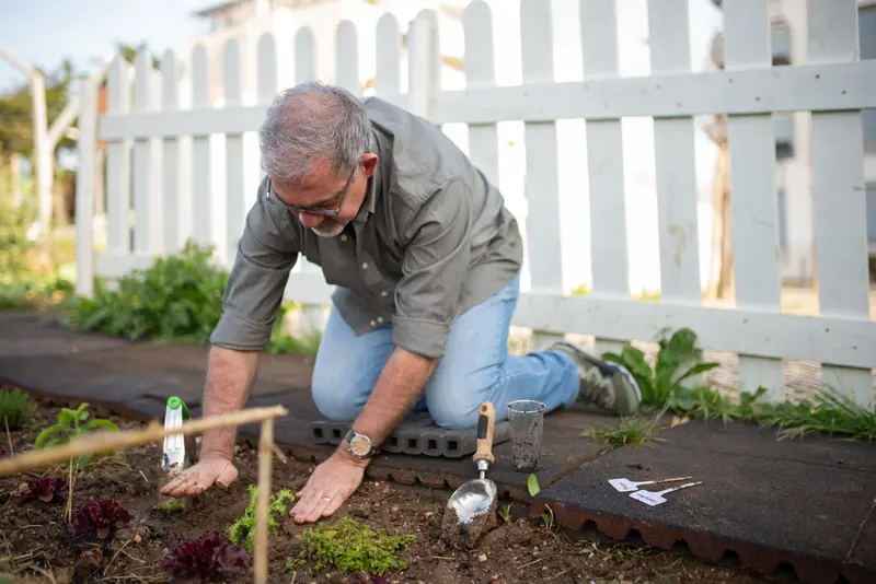 A patient on his knees planting the spring garden