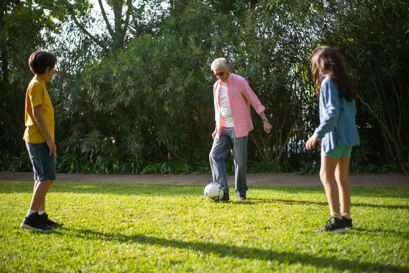 A grandfather playing soccer with his grandchildren