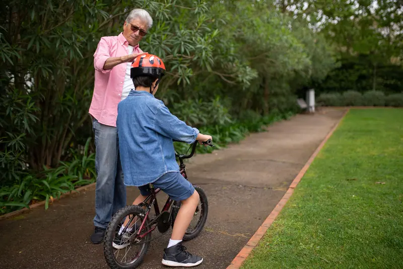 A grandfather teaching a boy to ride a bike
