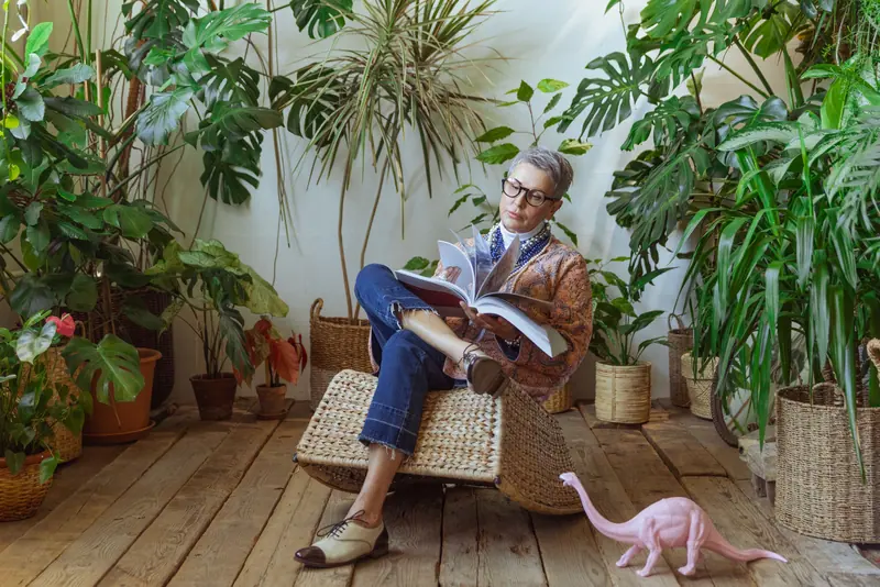 A woman reading among her houseplants