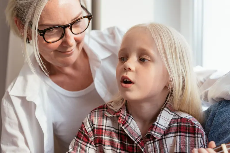 A grandmother and granddaughter laughing by the window