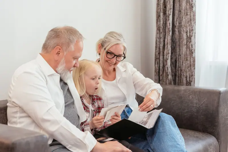Grandparents looking through an old photo album with their granddaughter