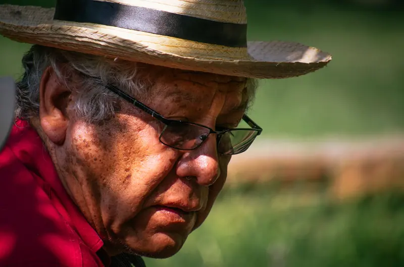 A patient in a straw hat in his garden on a summer afternoon