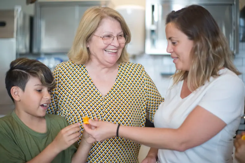 Three generations laughing together in the kitchen