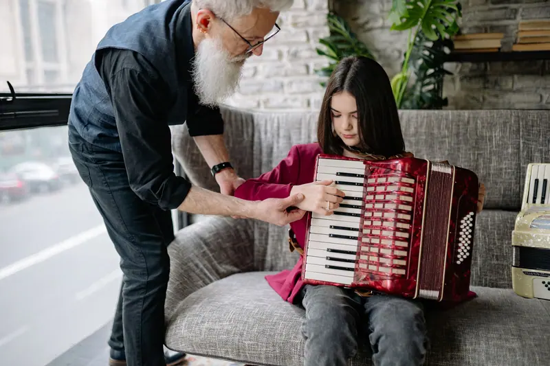 A grandfather teaching his granddaughter the accordion