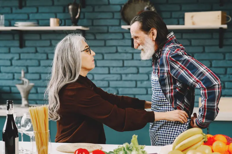 A wife tying her husband's apron in the kitchen