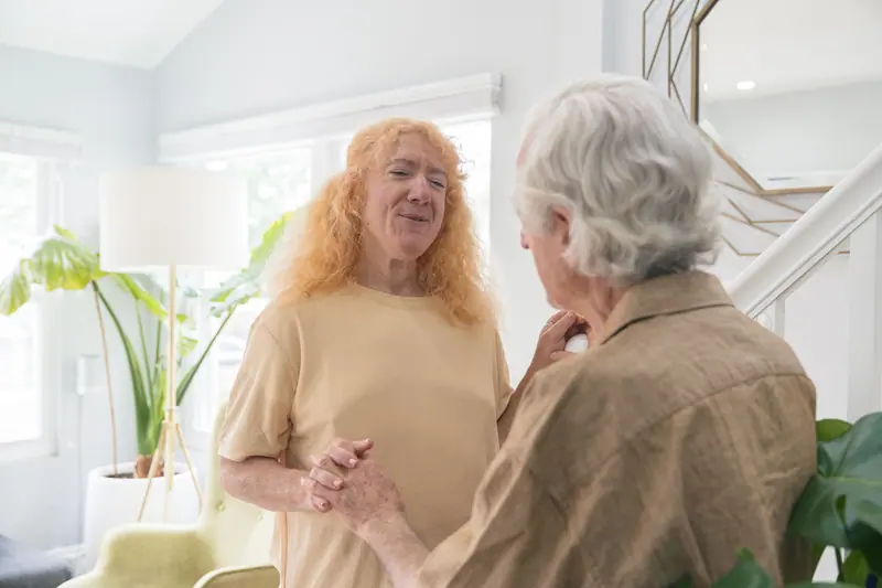 An older couple holding hands and smiling at home