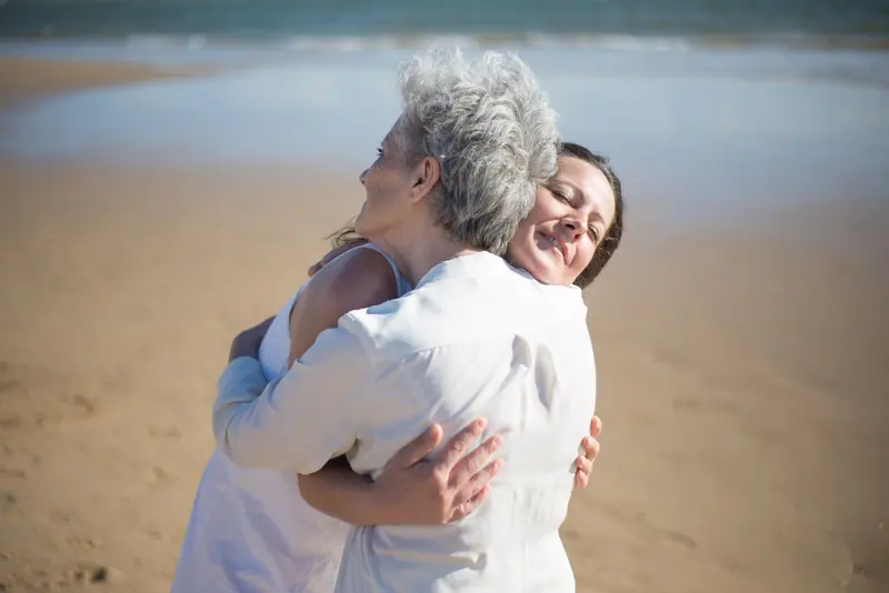 A mother and daughter hugging on a sunny afternoon