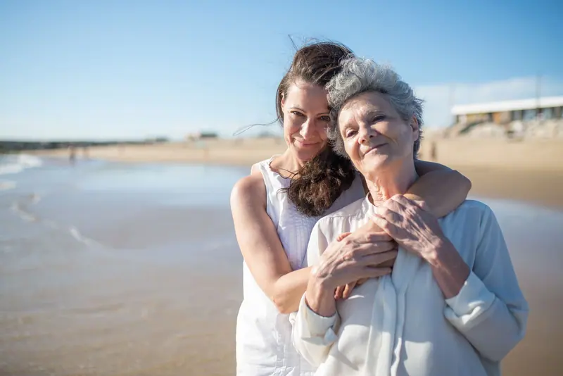 A daughter holding her mother close on a sunny afternoon