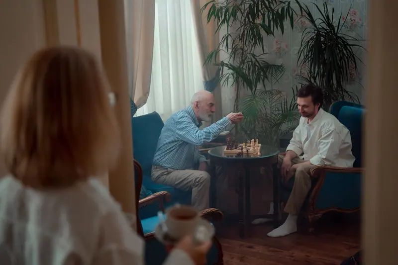A patient playing chess with his son by the window
