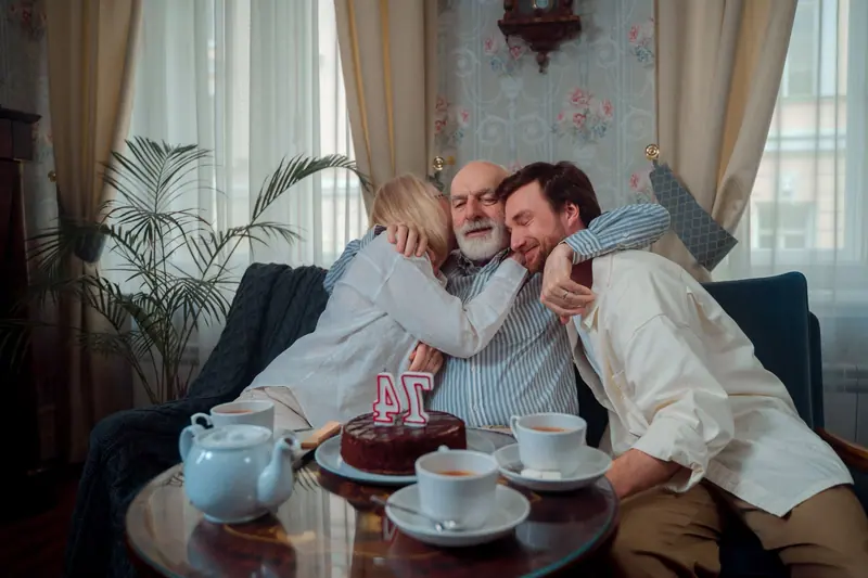 A family crowding around Grandpa with a birthday cake