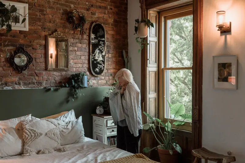 A woman at home in her bedroom with brick walls