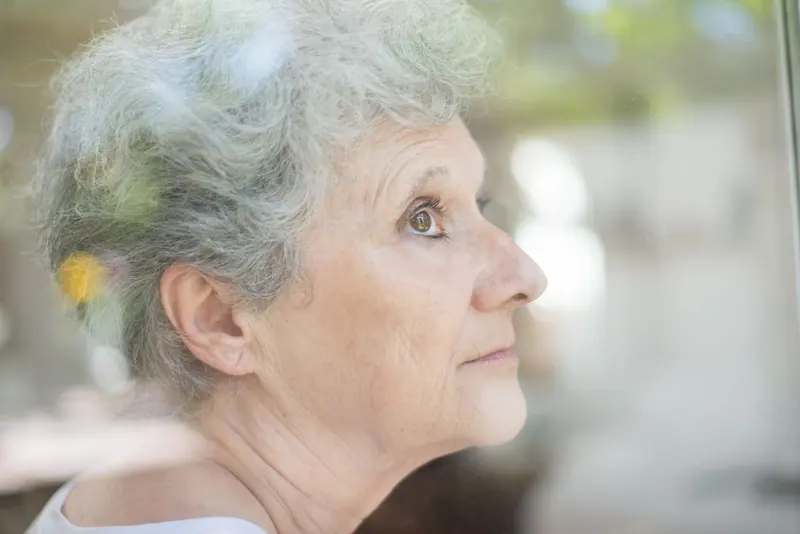 A patient gazing out her kitchen window in soft morning light