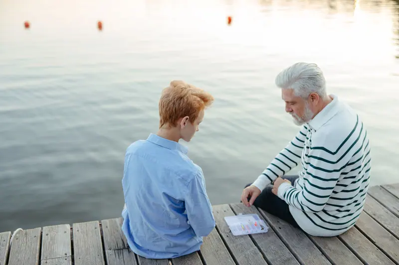 A grandfather and grandson sitting on the dock in the evening light