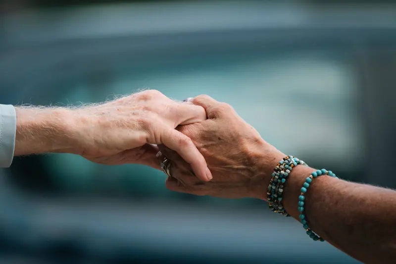Two hands, one older and one younger, holding each other
