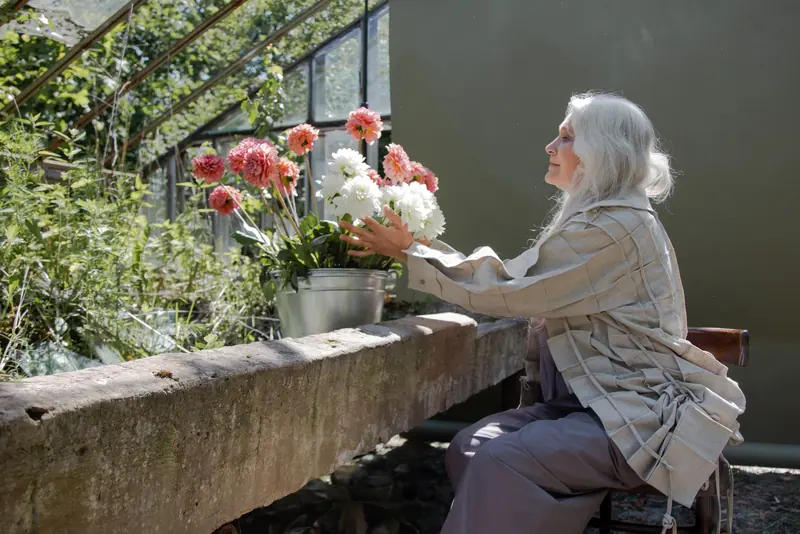 A resident cutting zinnias and dahlias in the greenhouse first thing in the morning