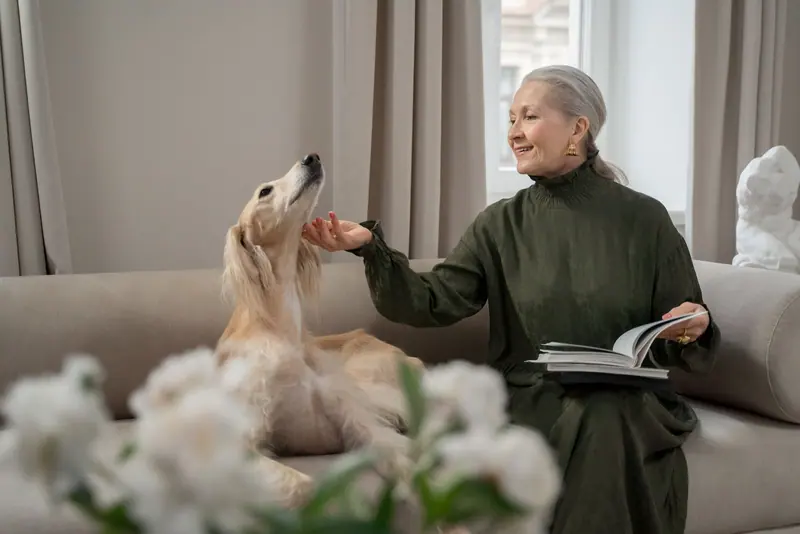 A resident reading on the sofa while a saluki leans in for a pat