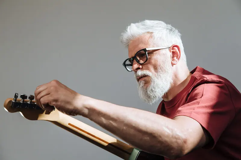 A resident with silver hair tuning his guitar
